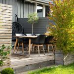 A patio with a table and chairs next to a fence