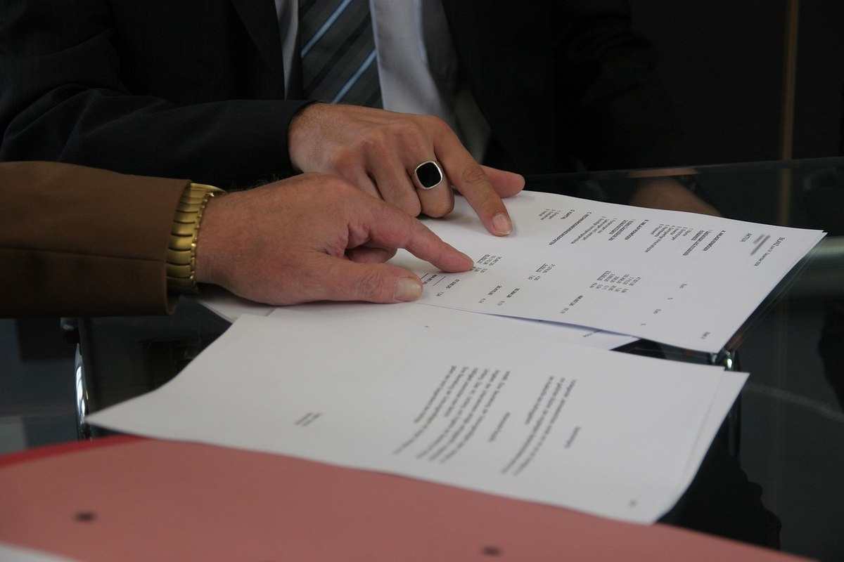 Deux personnes examinent et signent des papiers sur une surface transparente