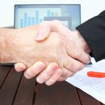 Deux mains se serrant sur une table en bois